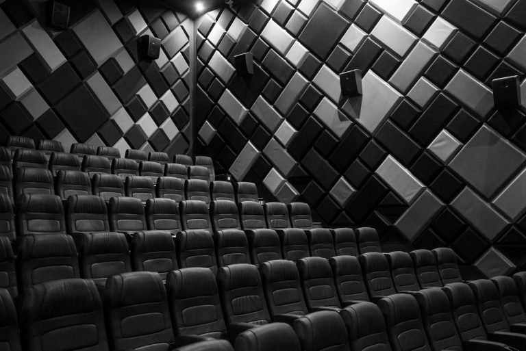 Interior of an empty cinema hall with leather seats and acoustic walls in grayscale.