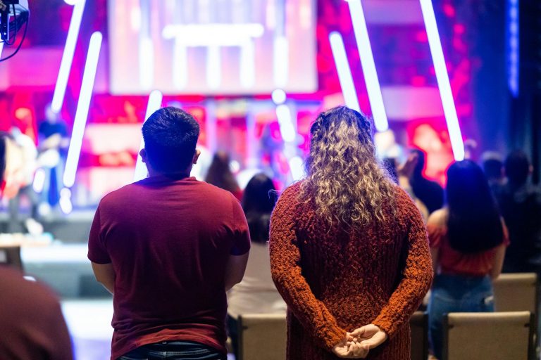 People attending a lively theater event with colorful neon lighting.