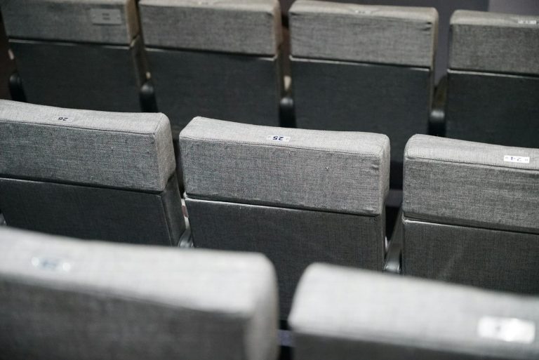 Close-up of empty gray theater seats arranged in neat rows. Perfect for cinema and event scenes.