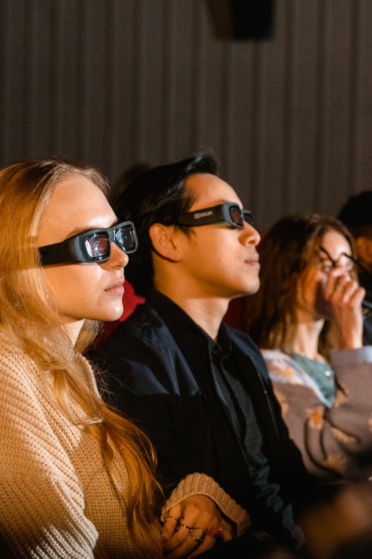 Group of people wearing 3D glasses watching a movie in an auditorium.