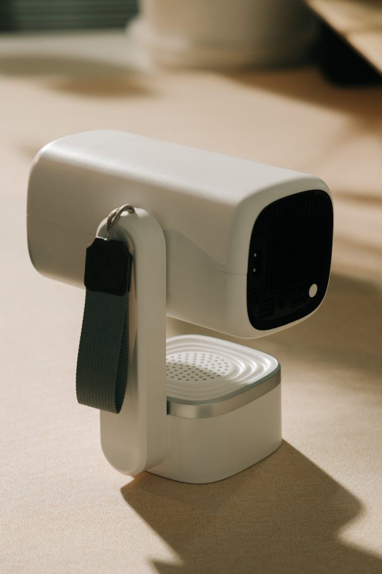 Sleek white portable projector with a strap, perfect for home or travel use.